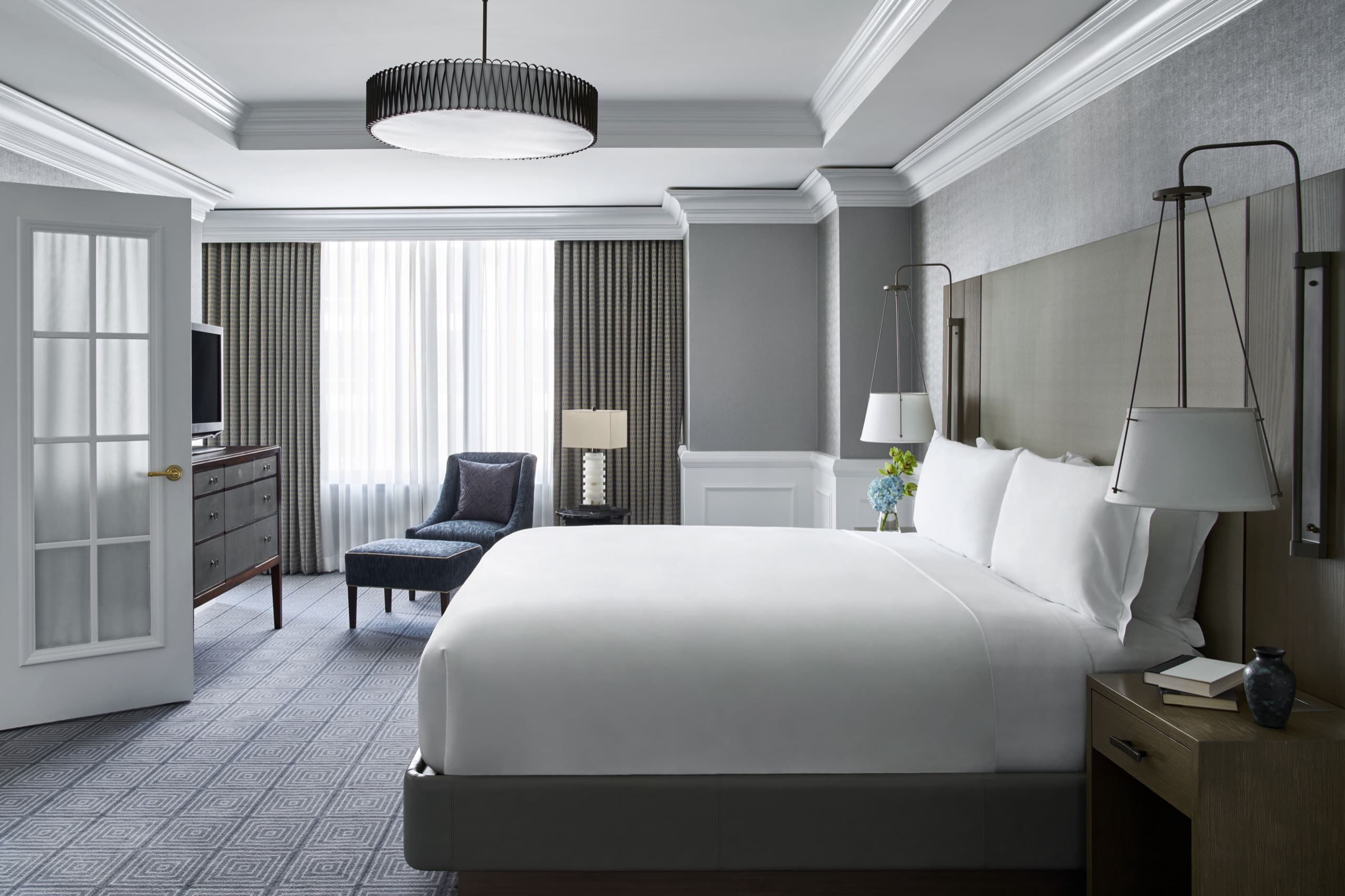 Deluxe king guest room — slate-grey palette, tufted headboard, brass accents