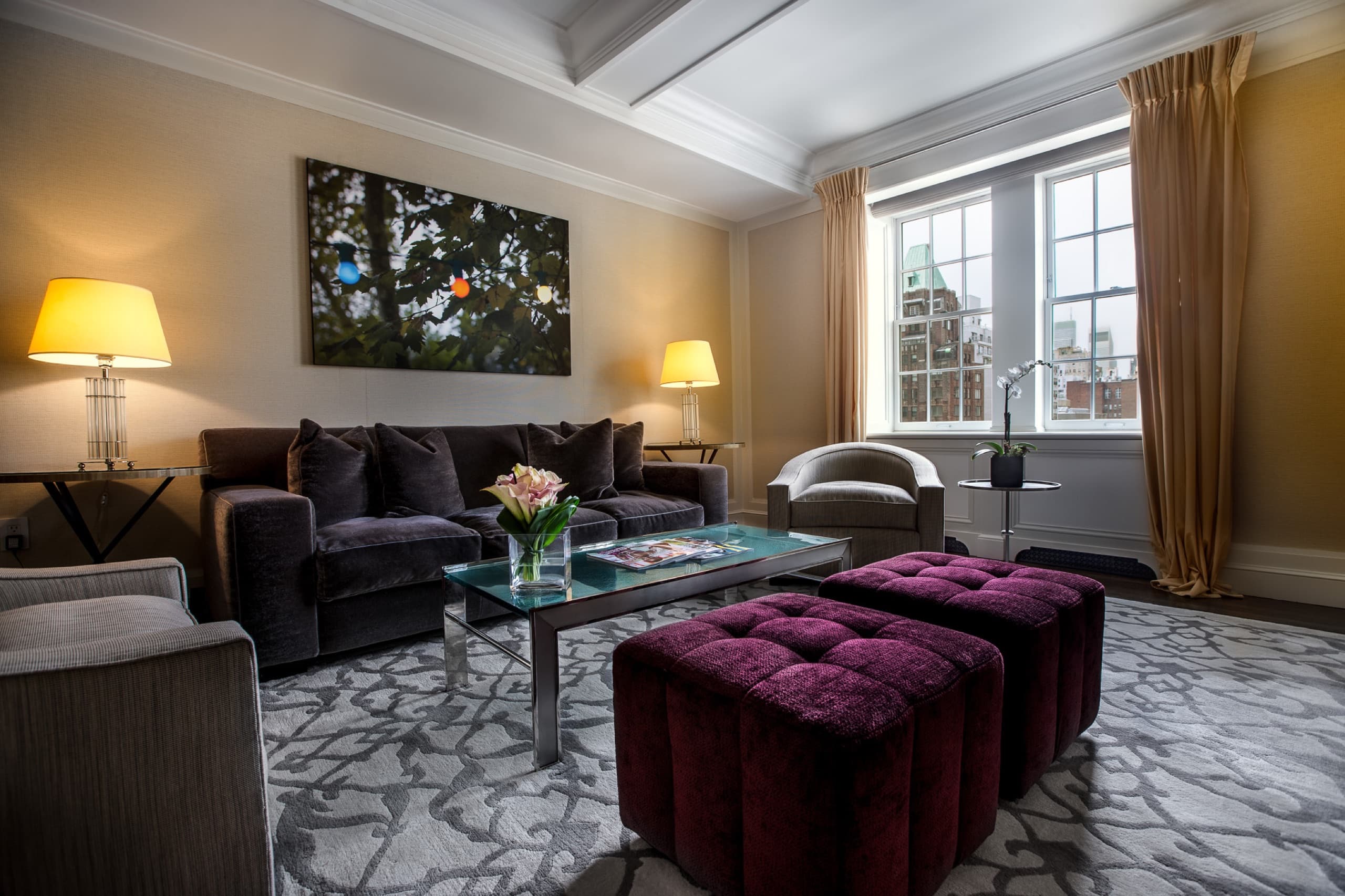 Premier Suite living room with tufted plum ottomans
