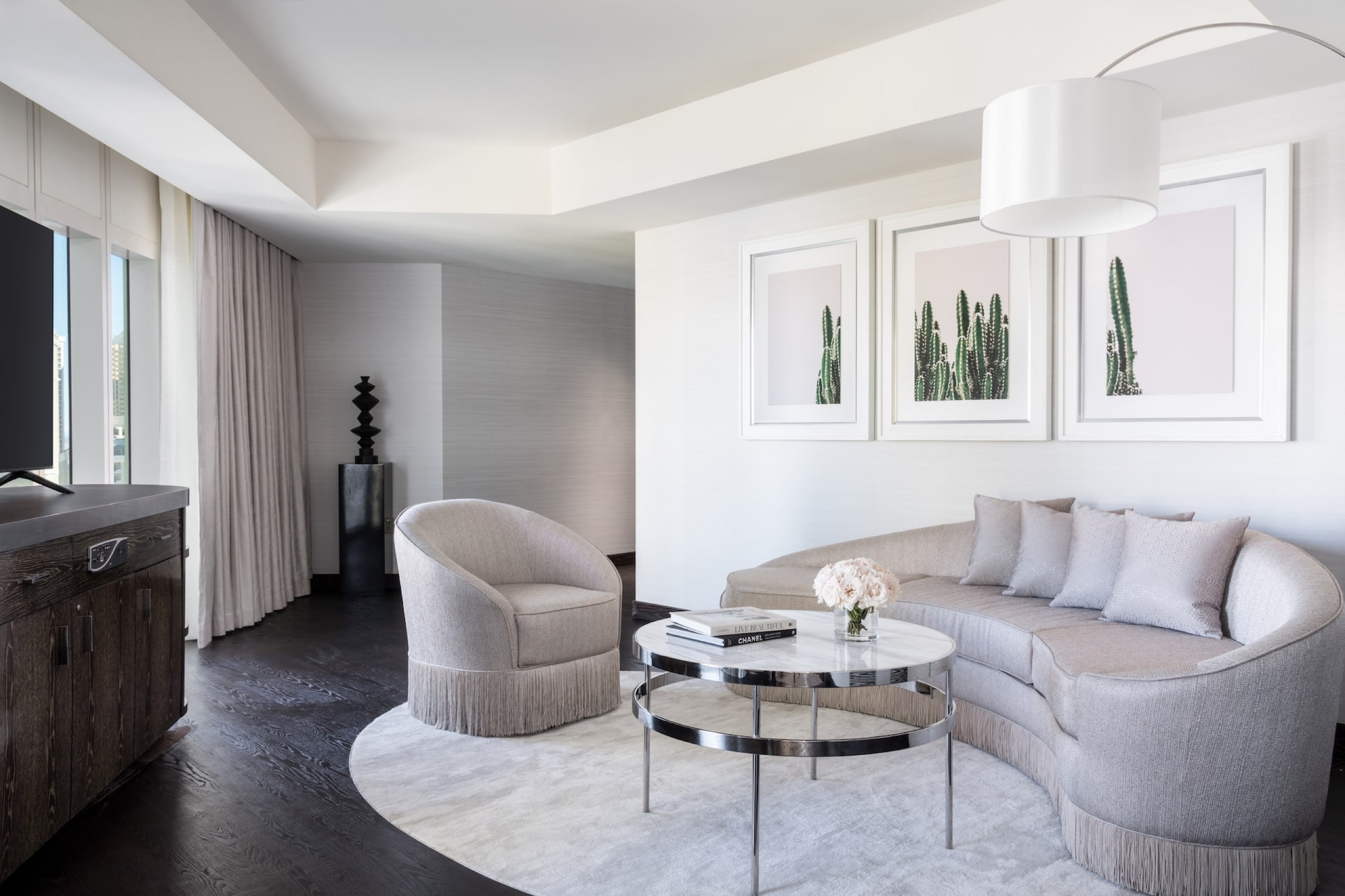 One Bedroom City View Suite - living room with curved sofa and cactus triptych