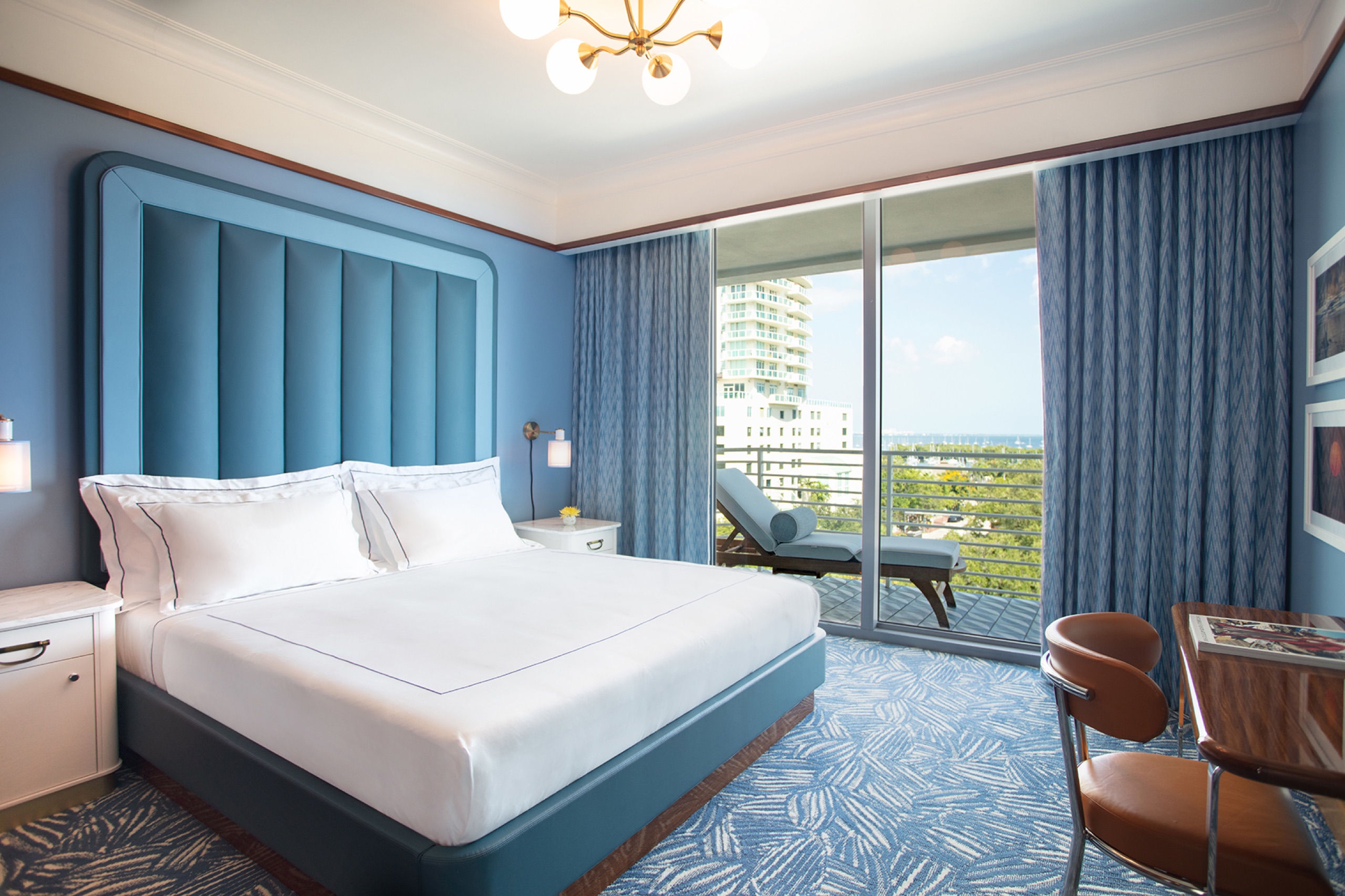 C Suite (One Bedroom): bedroom with blue headboard and terrace facing the Coconut Grove skyline