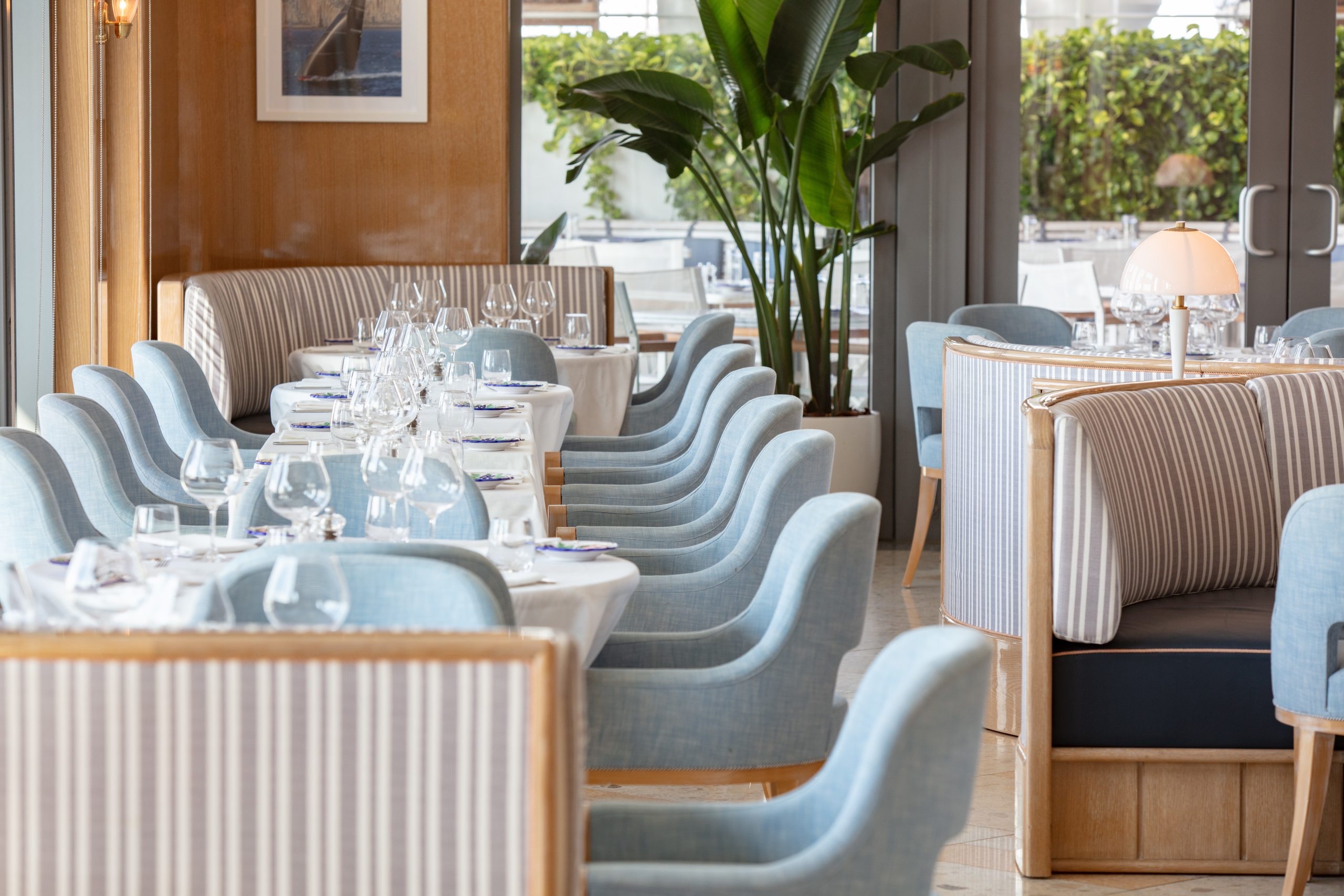 Bellini rooftop restaurant interior: powder-blue armchairs, striped banquettes, palms and bay light