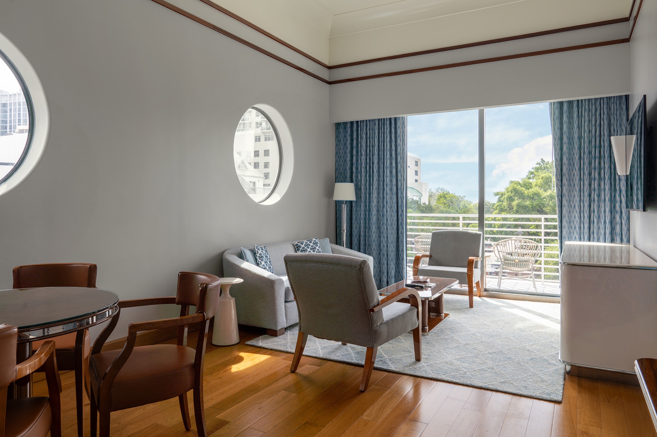 Classic Corner Suite (One Bedroom): corner living room with porthole windows, armchairs and wraparound terrace