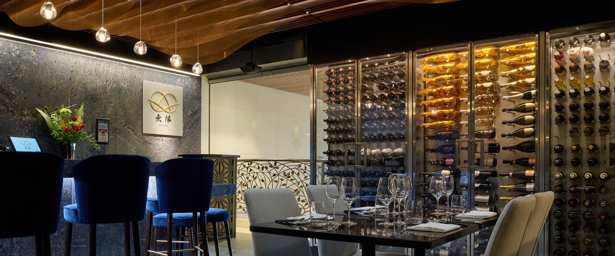 Mugen dining room with bar seating and illuminated wine wall