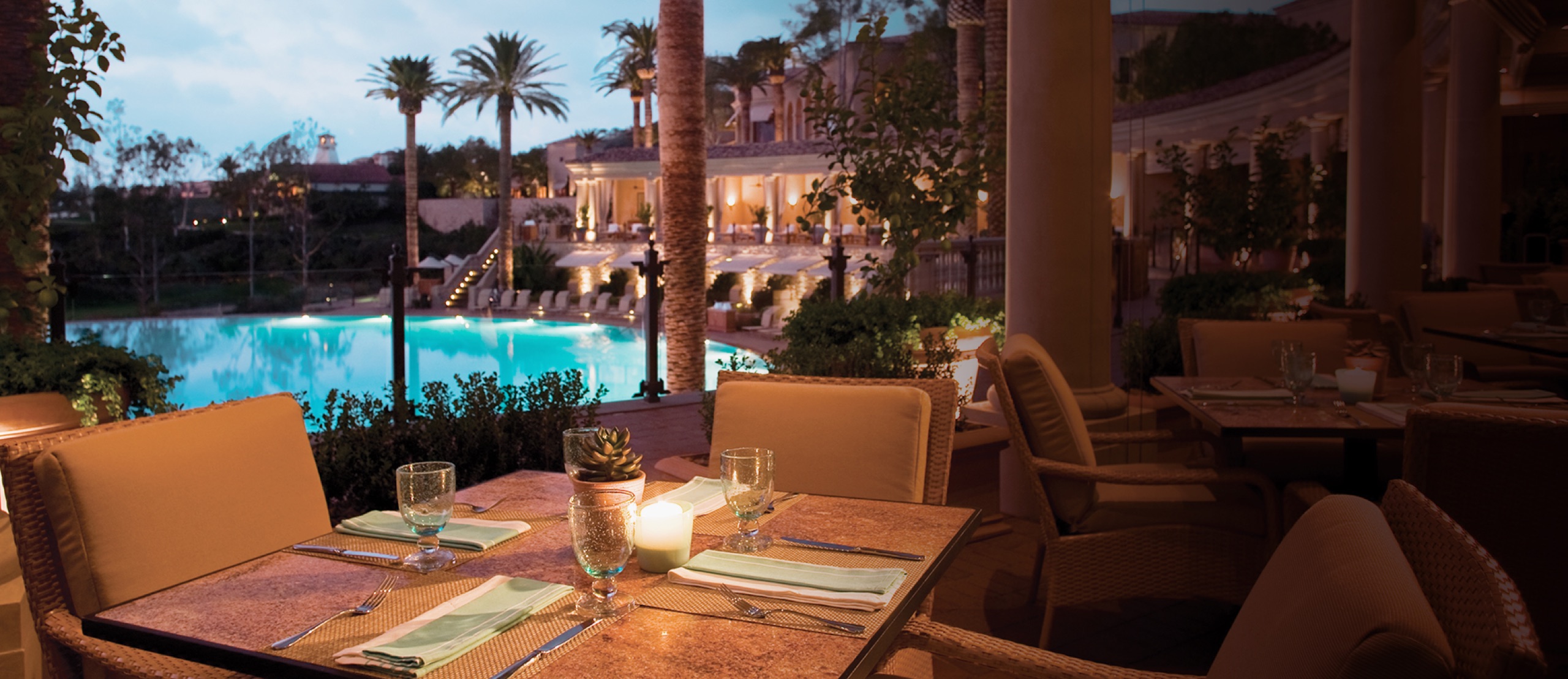 Coliseum Pool & Grill — terrace table overlooking the pool at dusk