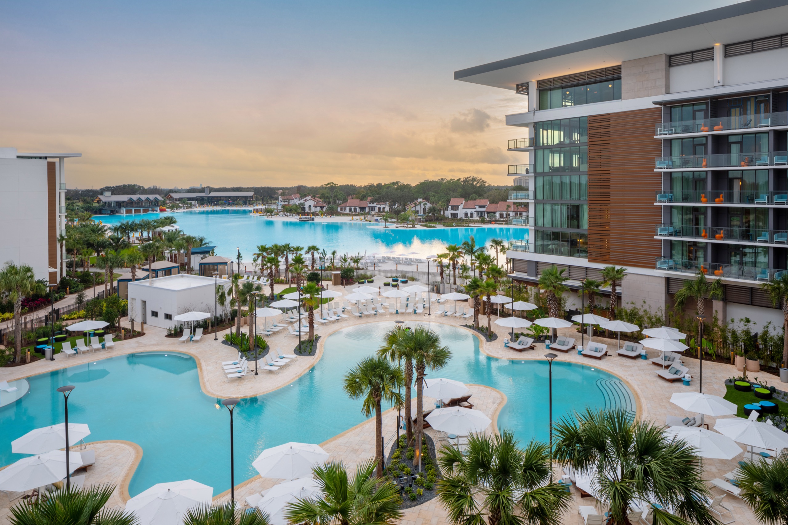 Resort pool complex at dusk with Evermore Bay lagoon behind (aerial)