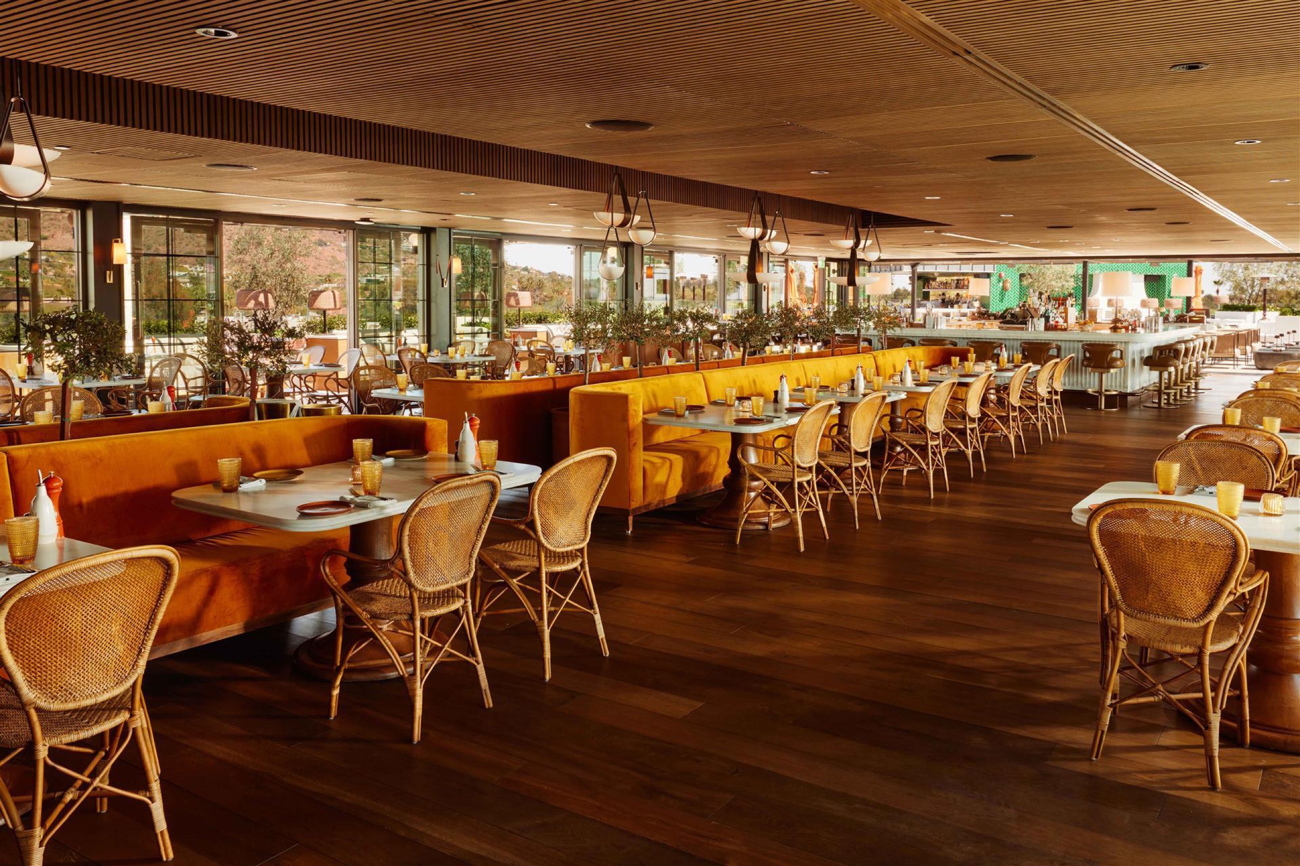 thea rooftop dining room with orange banquettes and rattan chairs